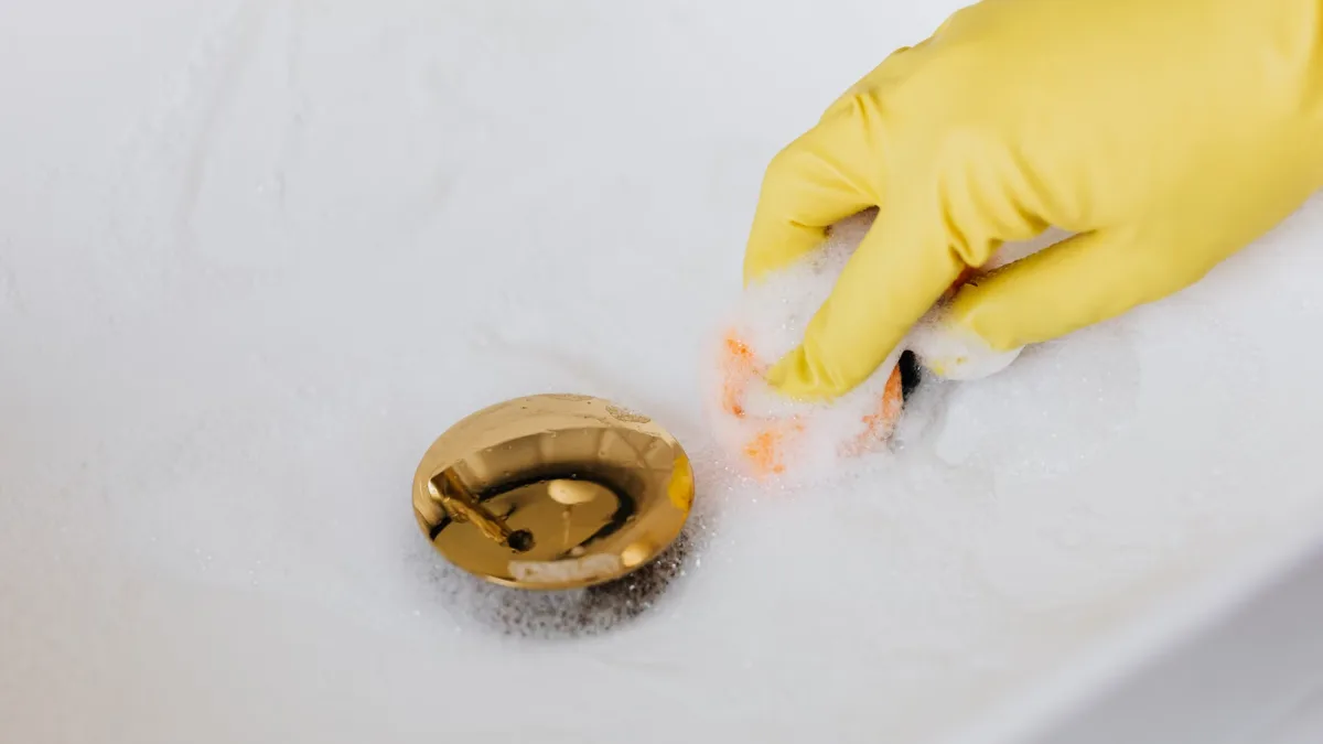 Gloved hand cleaning and disinfecting a floor drain